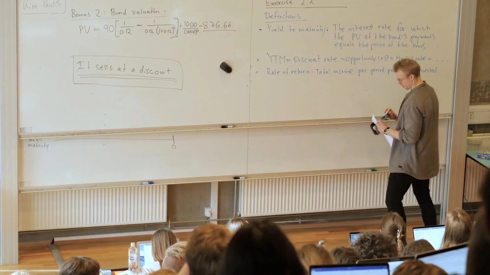 Kim teaching a lecture hall of students with laptops