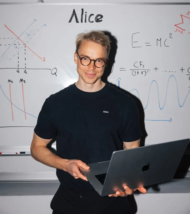 Kim in front of a whiteboard, holding a laptop
